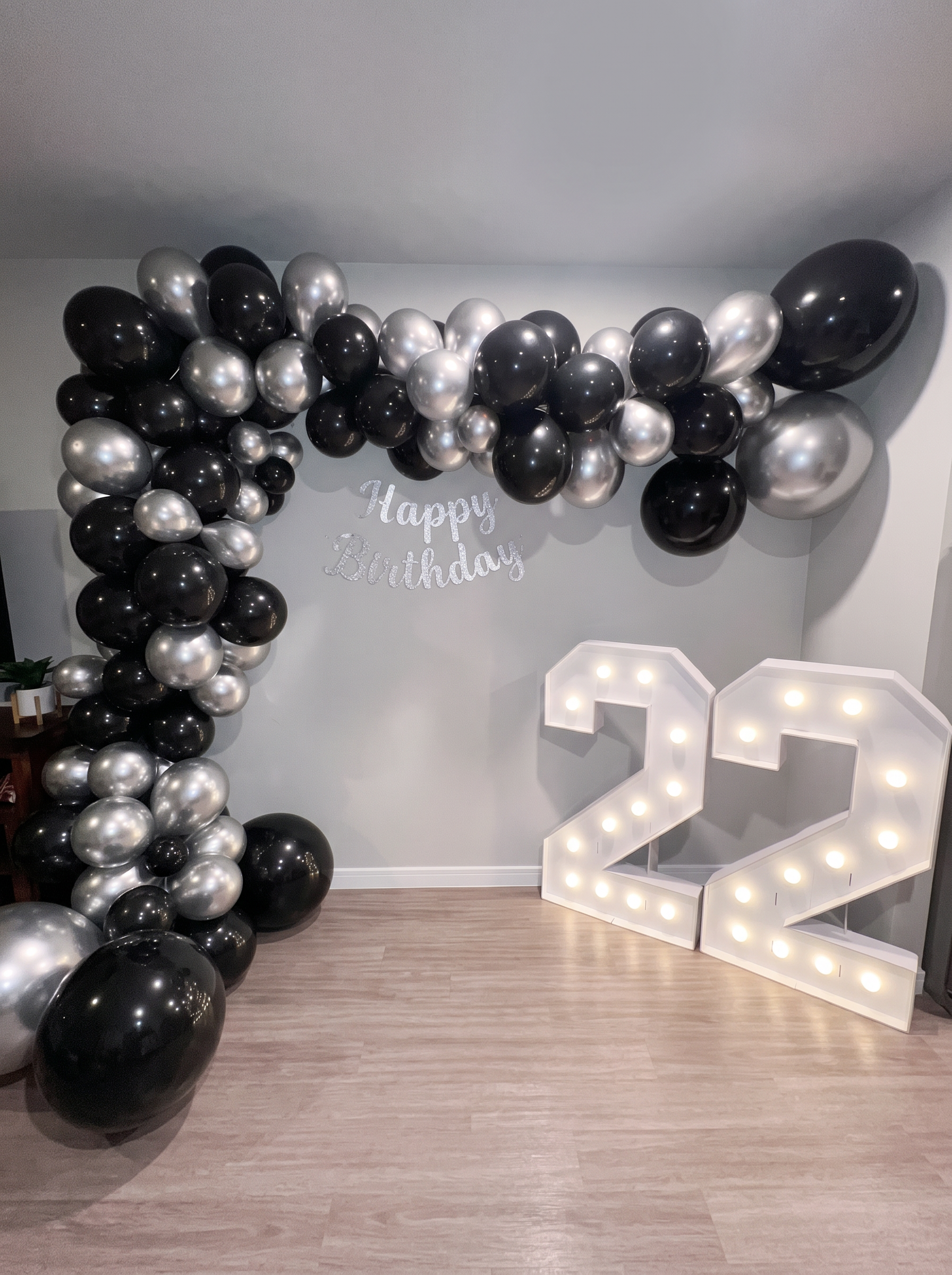 Black and silver balloon arch with lit marquee 22 numbers