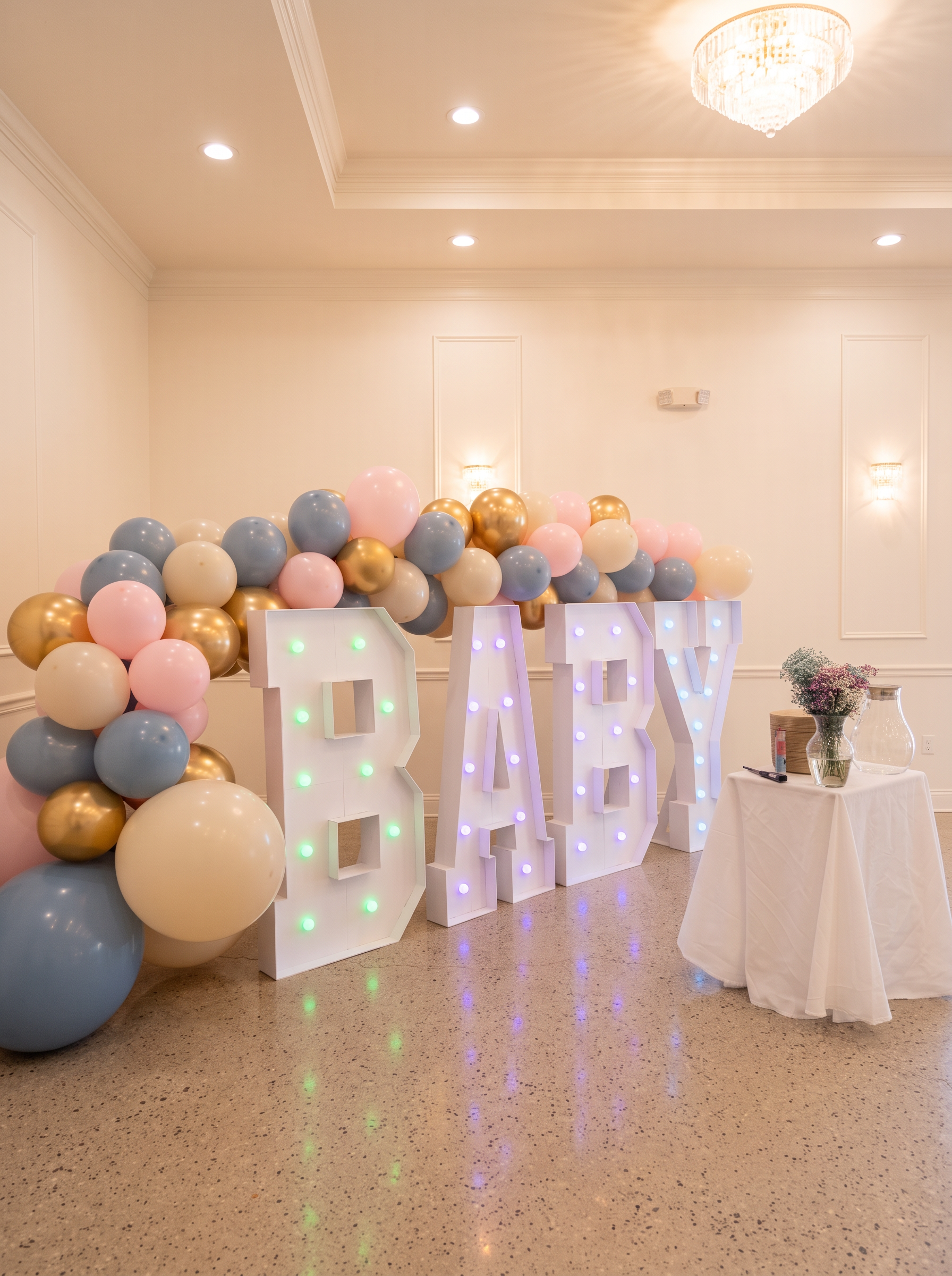 Pastel balloon garland with lit BABY marquee letters in an event hall